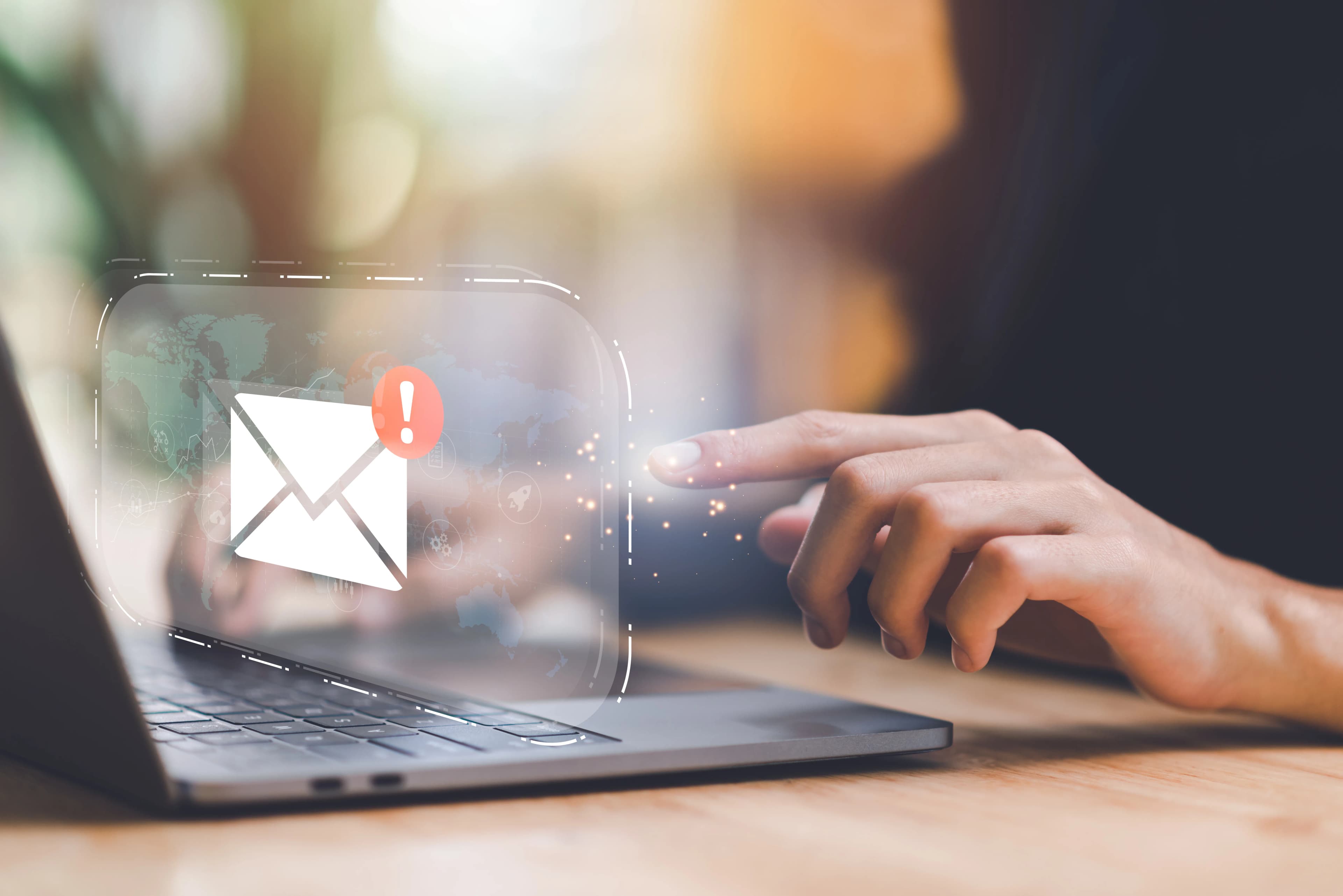 A new email notification icon above a hand working on a laptop