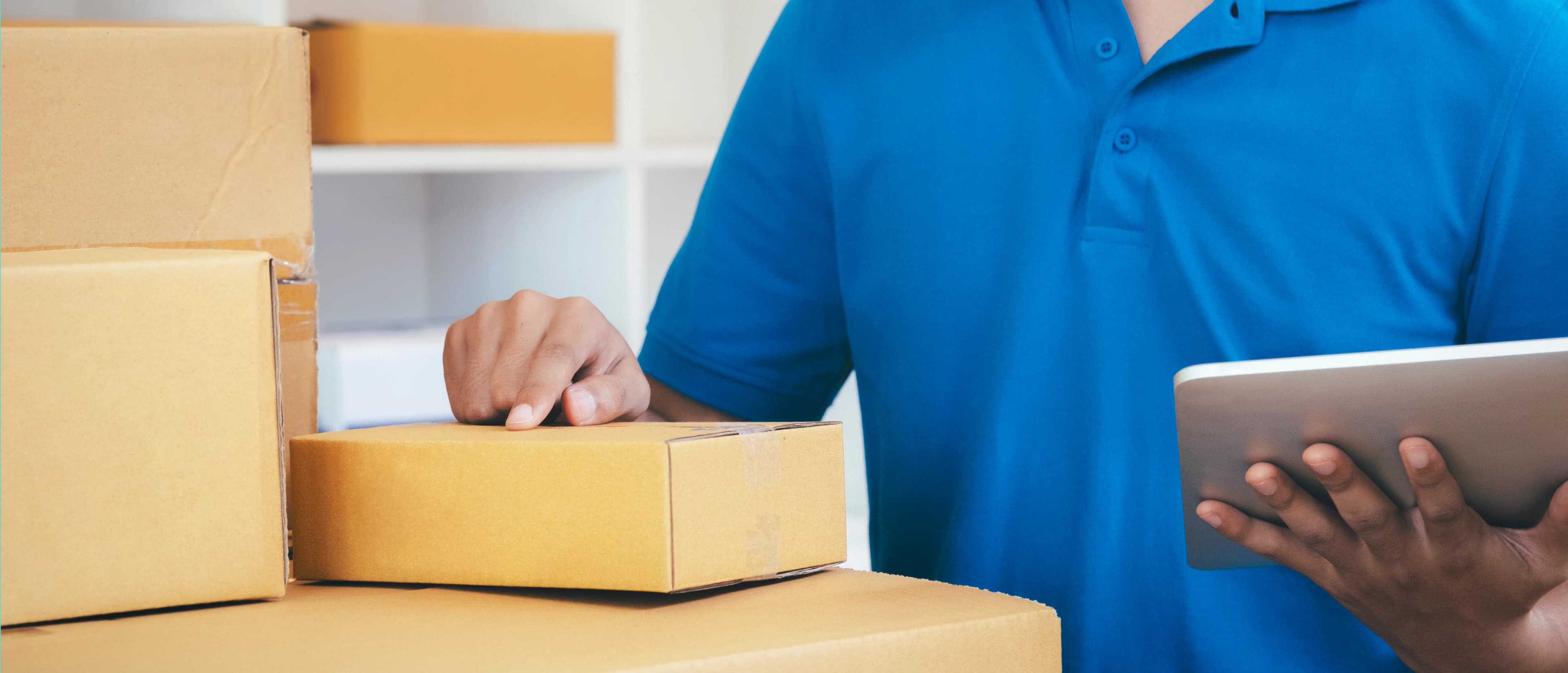 Worker checking a shipping list on a tablet next to parcel boxes
