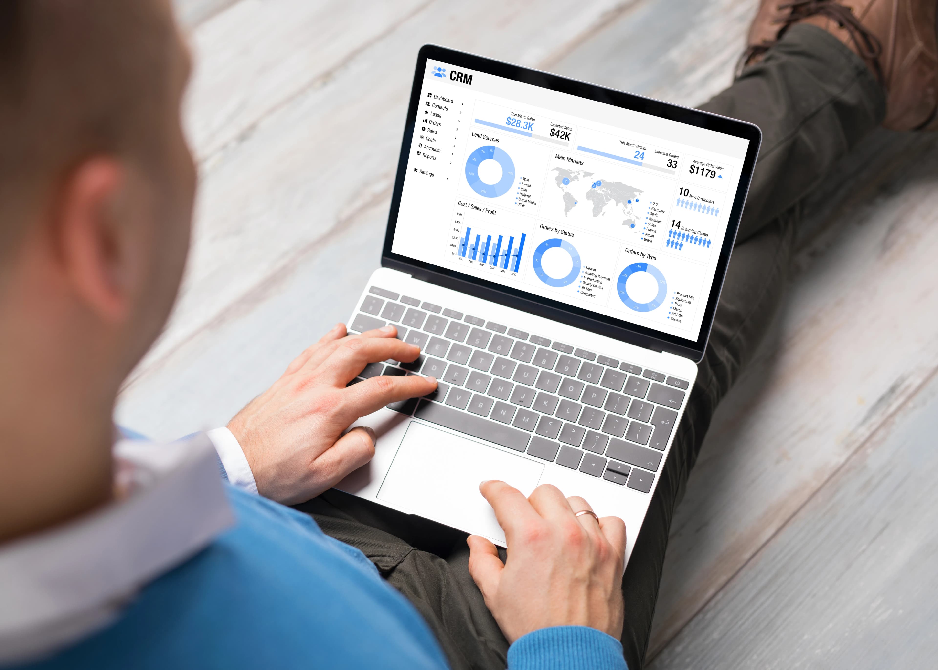 Laptop ekranında satış grafikleri gösteren CRM yazılımını kullanan bir adam
