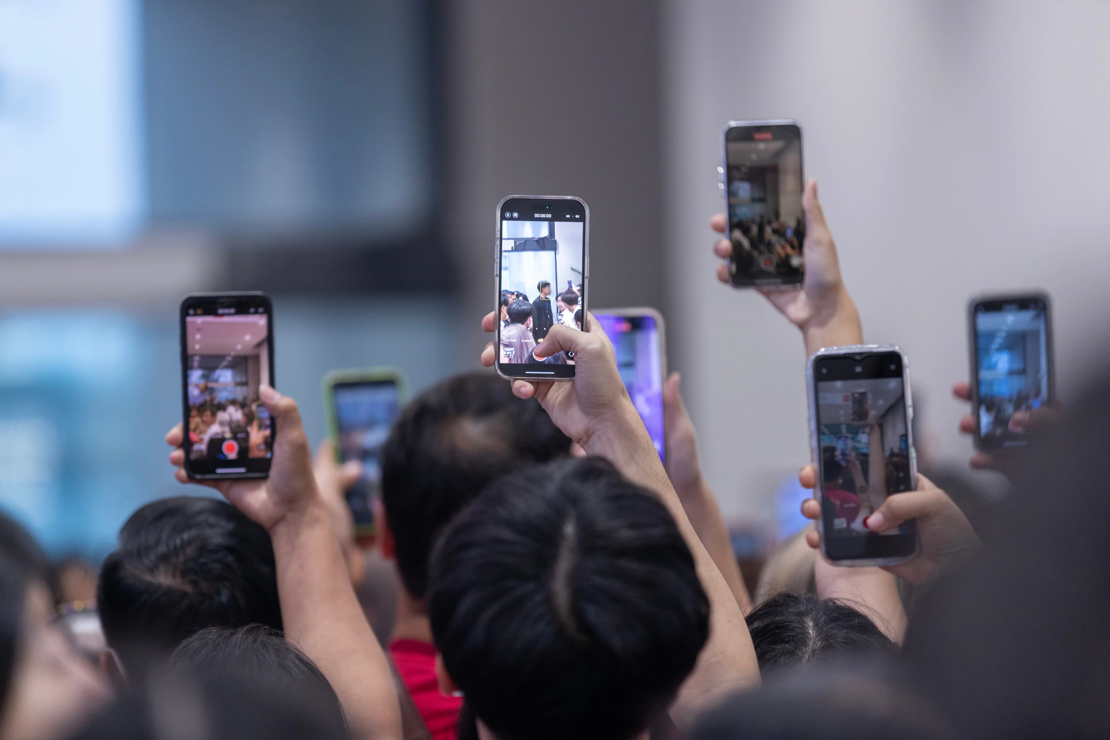 A crowd at a concert filming vertical video with their phones