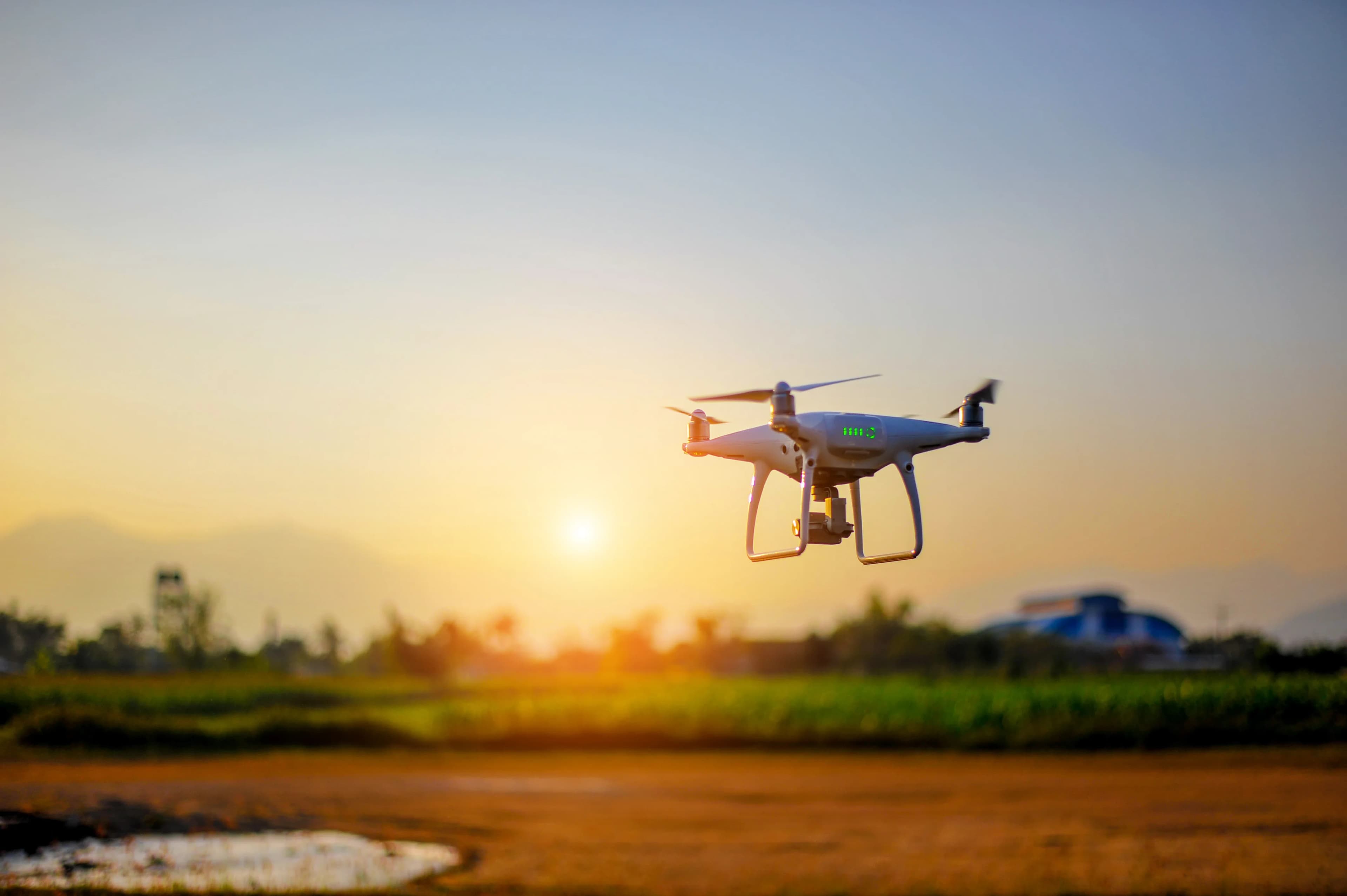 A camera drone flying over farmland at sunset