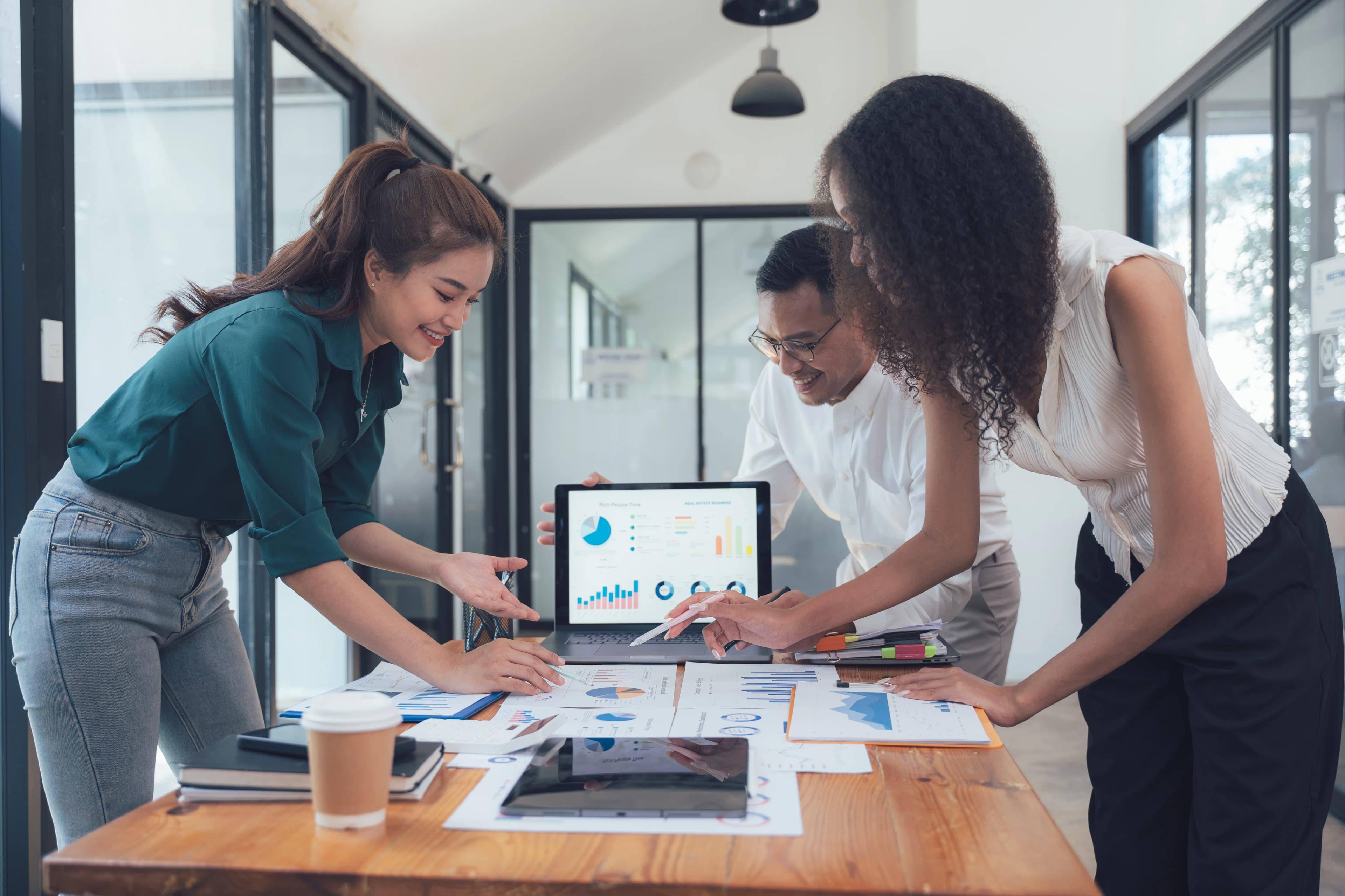 A team working together over a laptop and documents with charts in a meeting