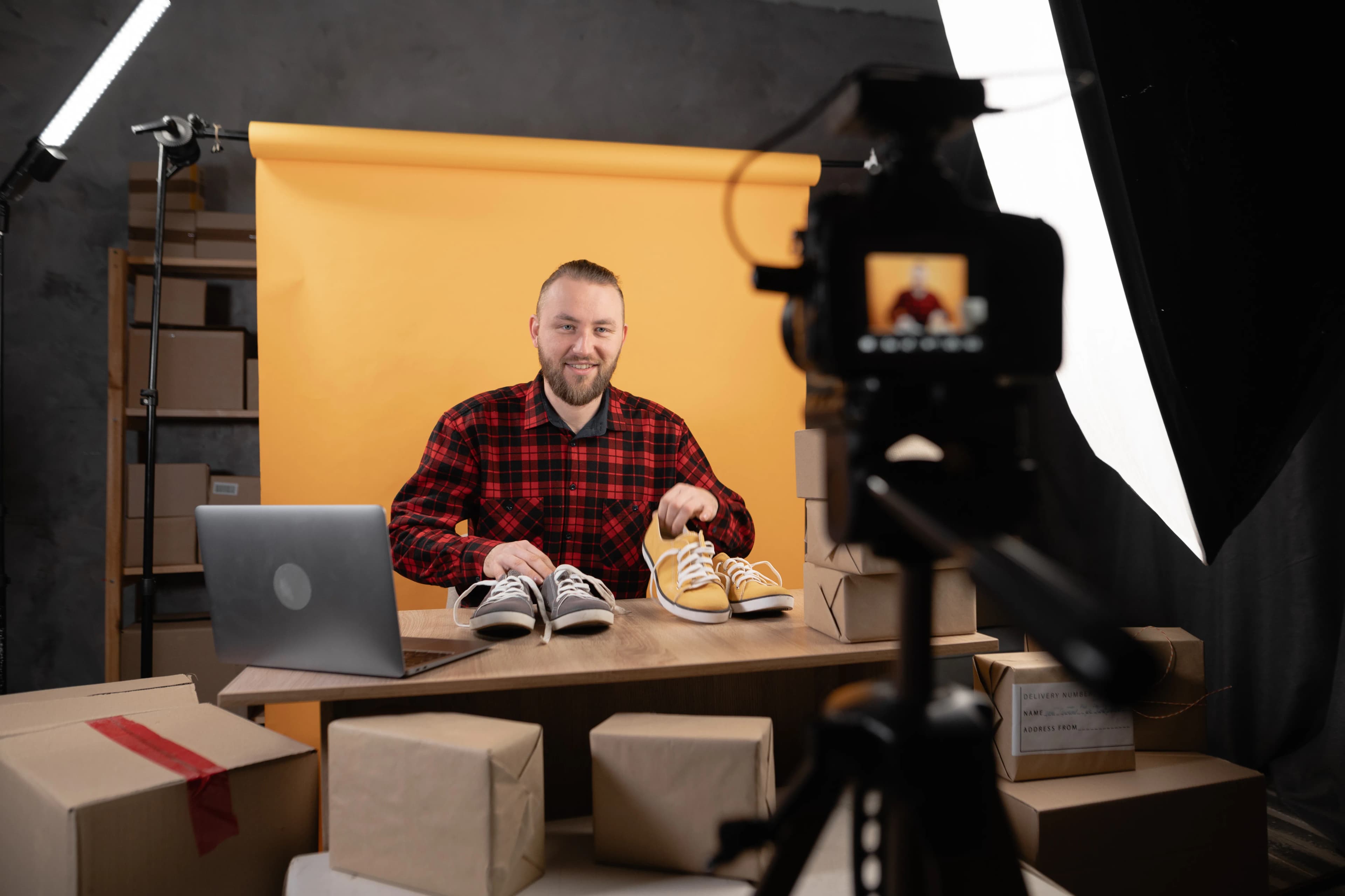 A vlogger presenting a product on a desk in front of a camera in a studio