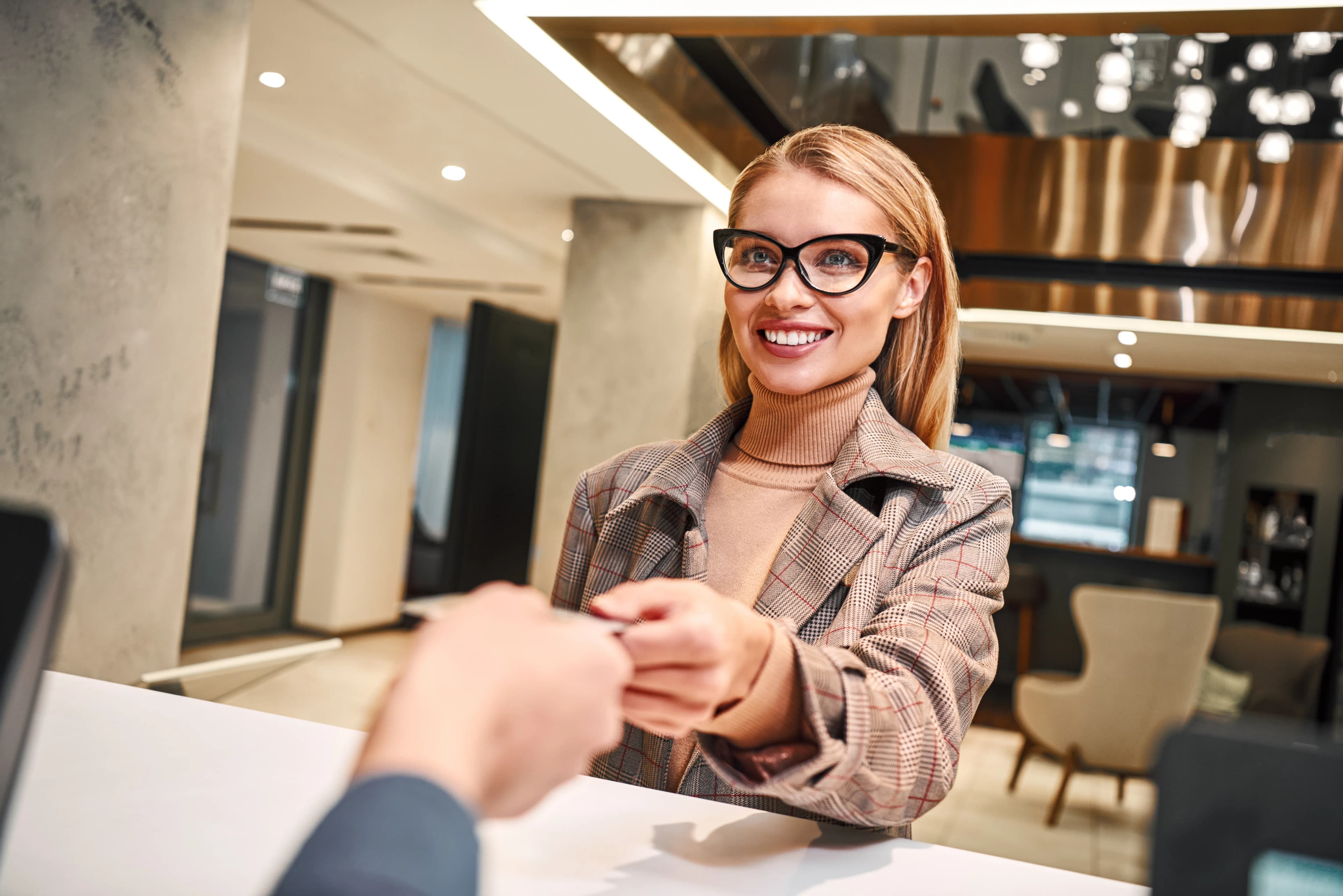 A guest checking in at a hotel reception being handed a key card