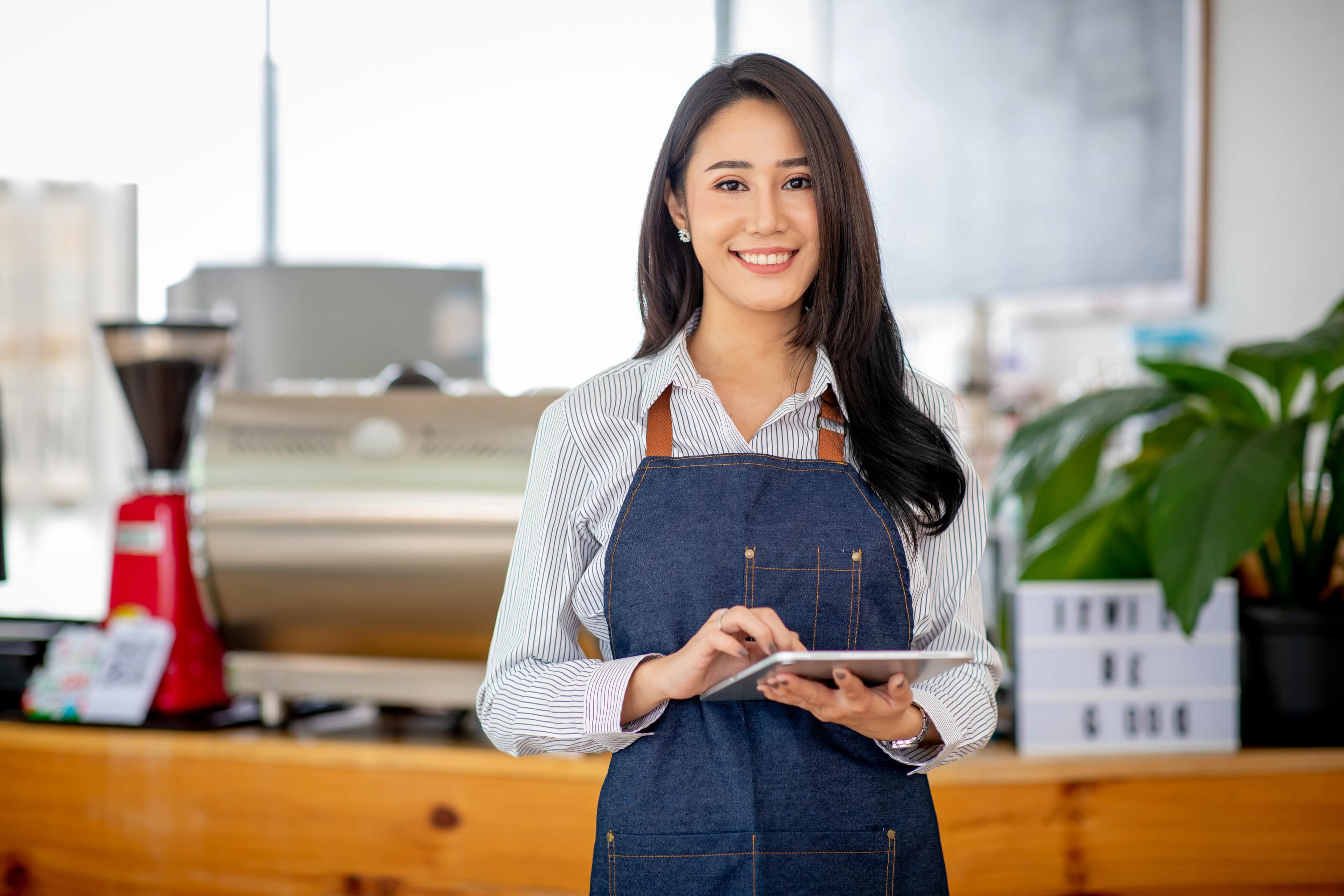 Cafe owner smiling with a tablet next to the counter