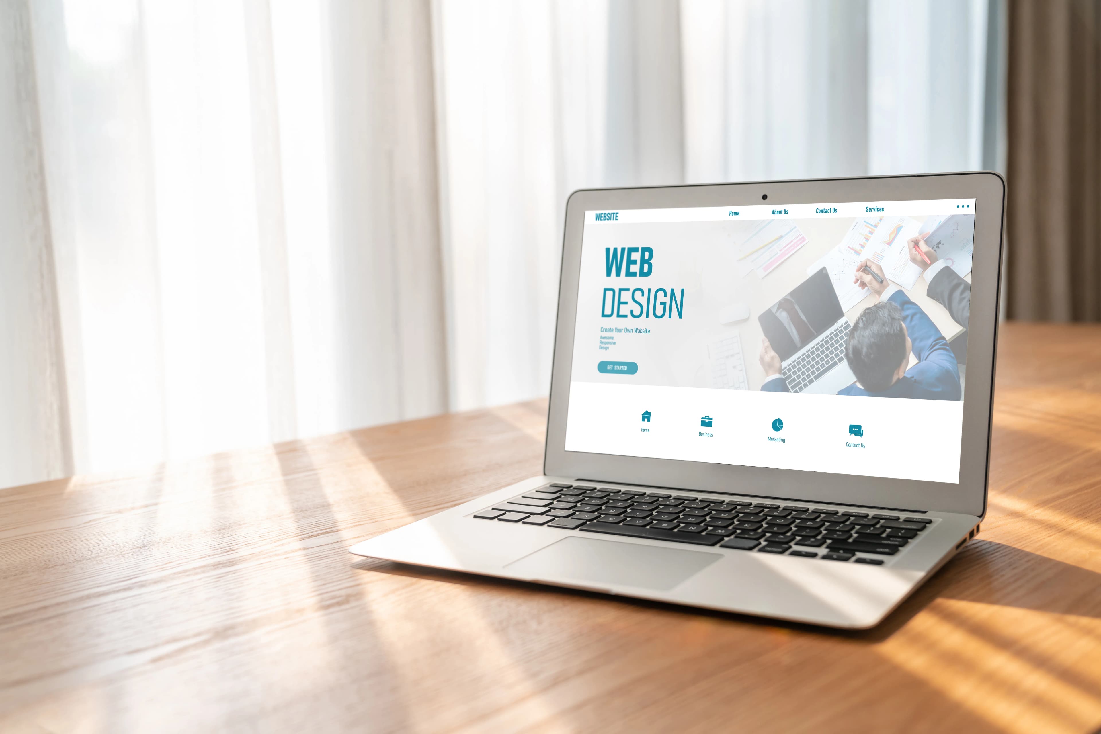 The homepage of a web design site on a laptop screen on a wooden desk