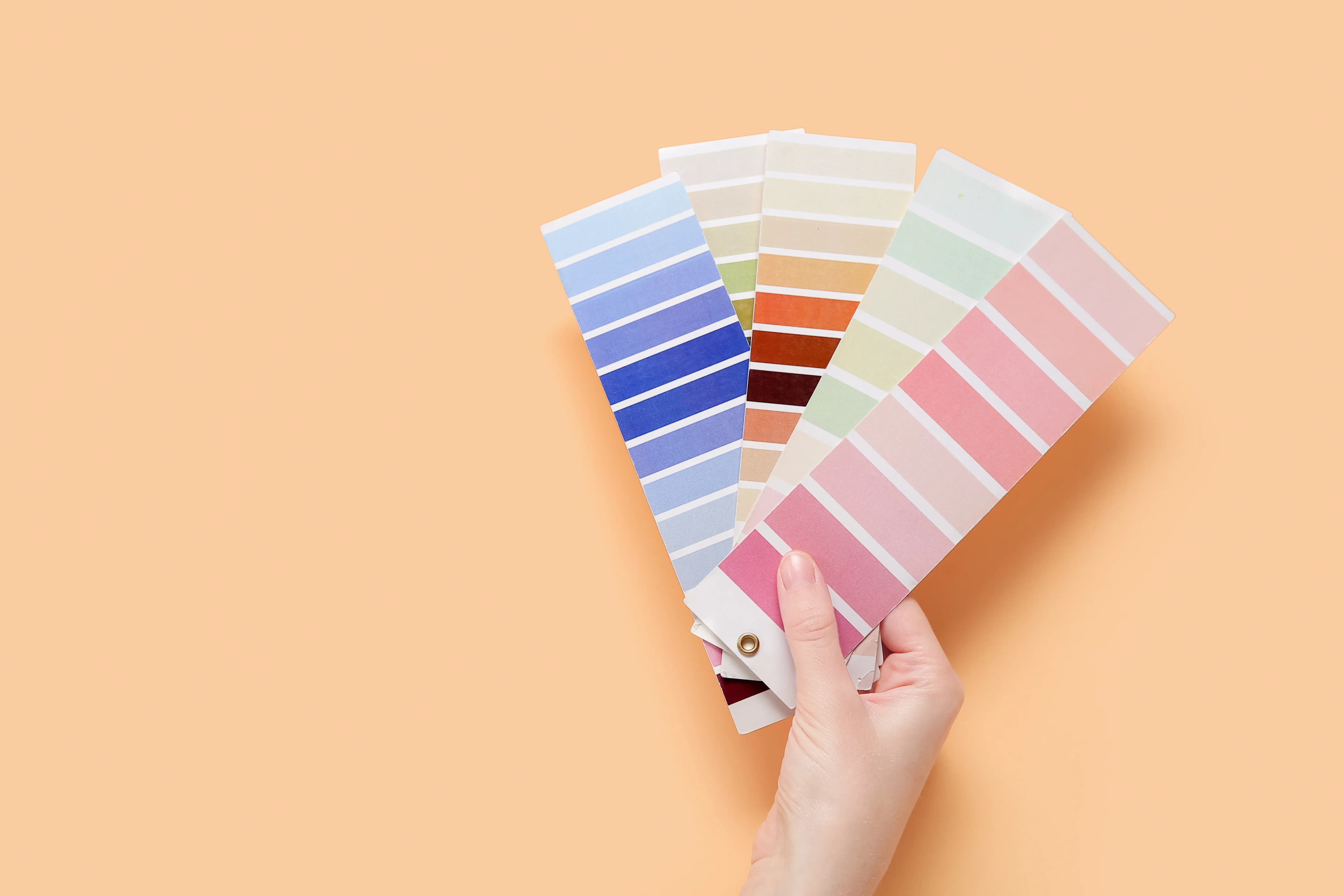 Fanned colour swatches held in a hand on a beige background
