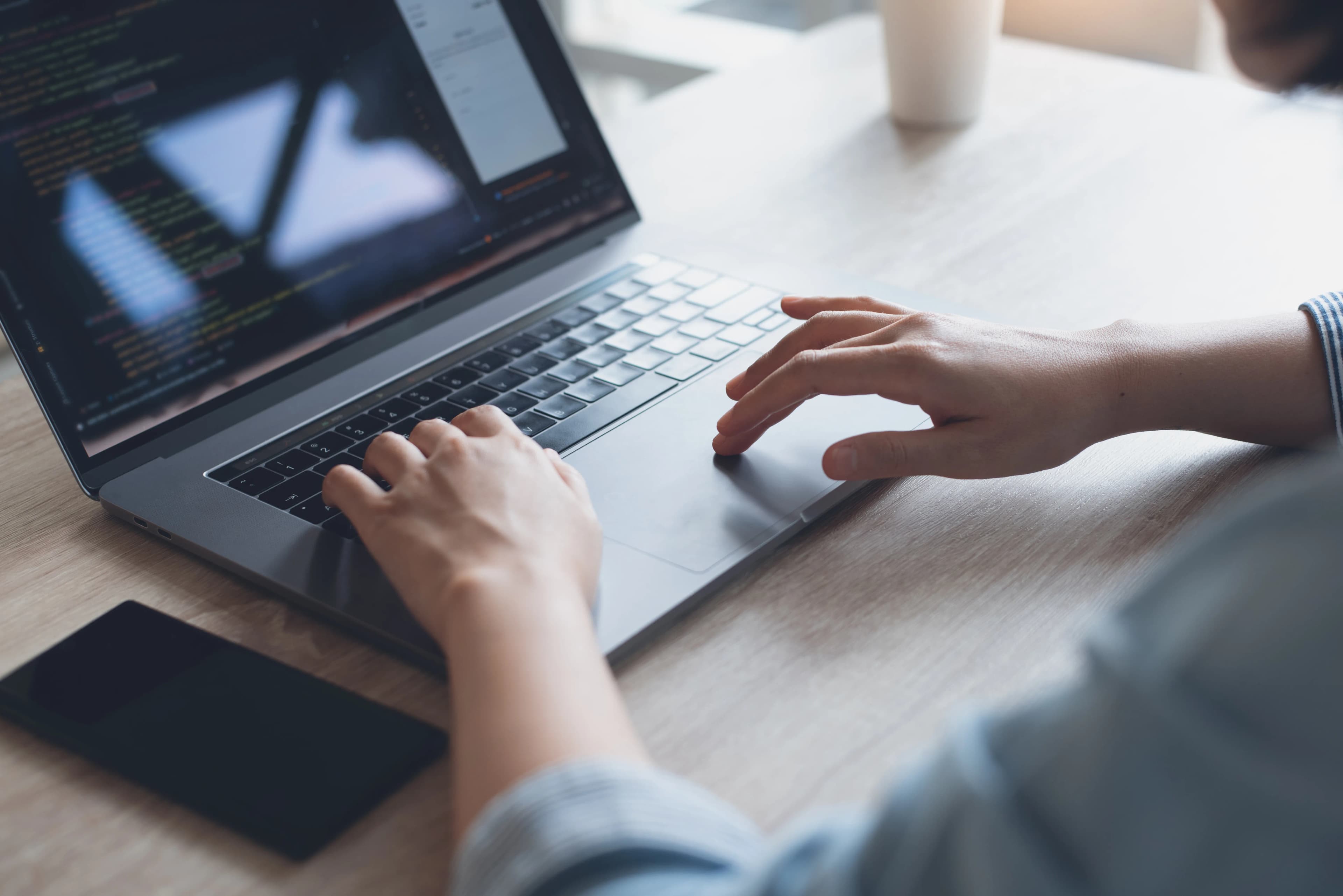 Close-up of a woman's hands writing code on a laptop