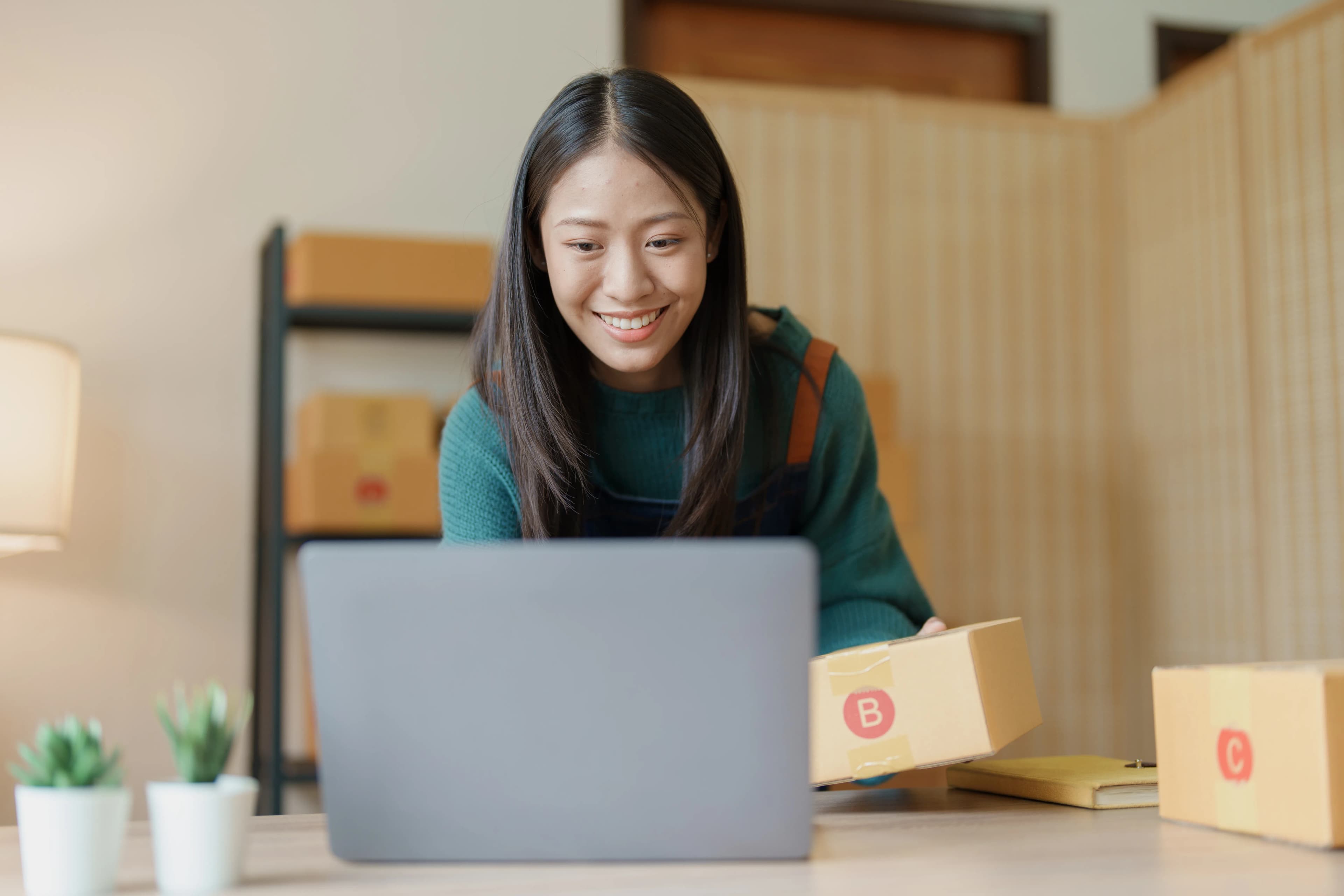 Online seller taking orders on a computer and packing products for delivery