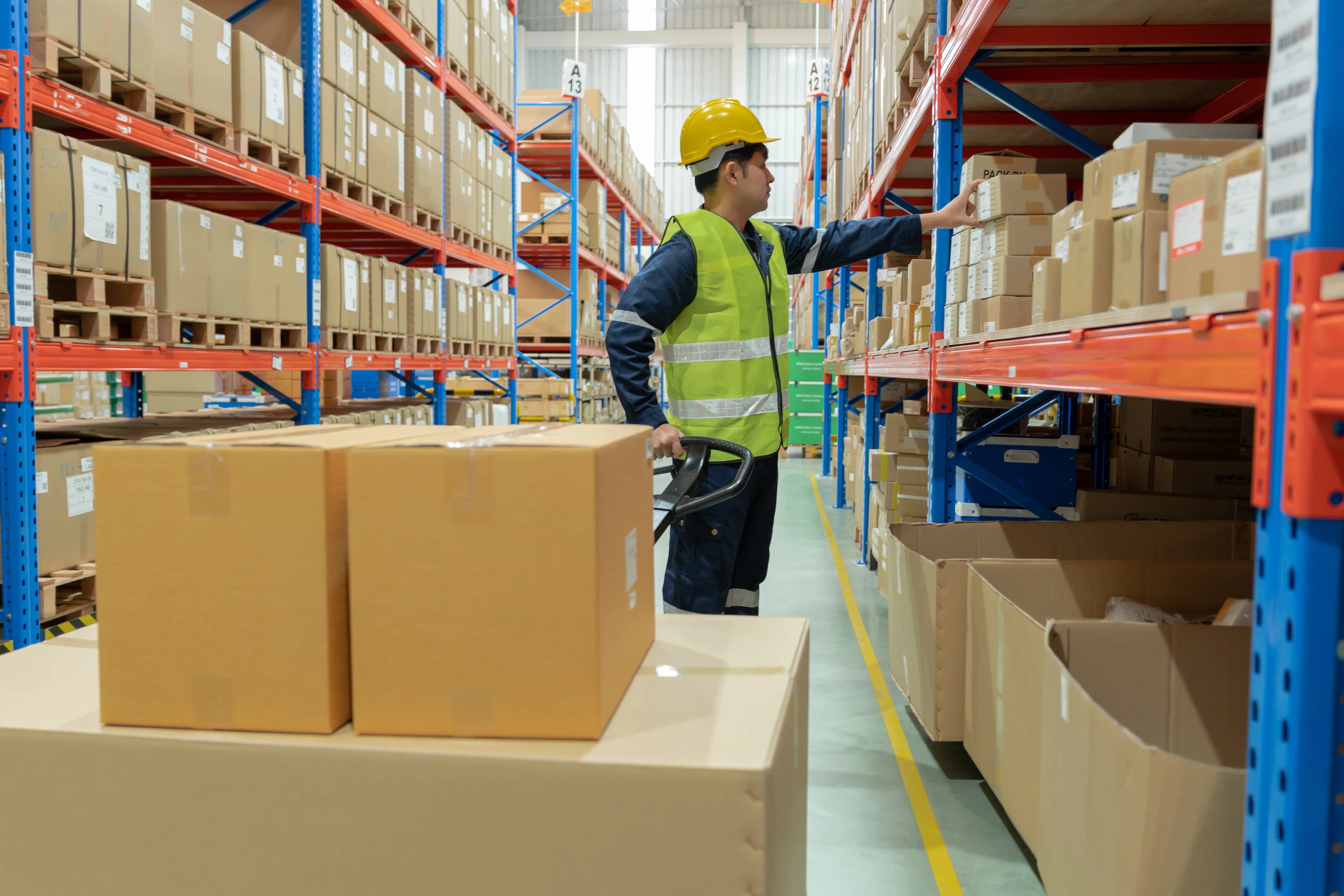Warehouse worker picking a box from the shelves while checking stock
