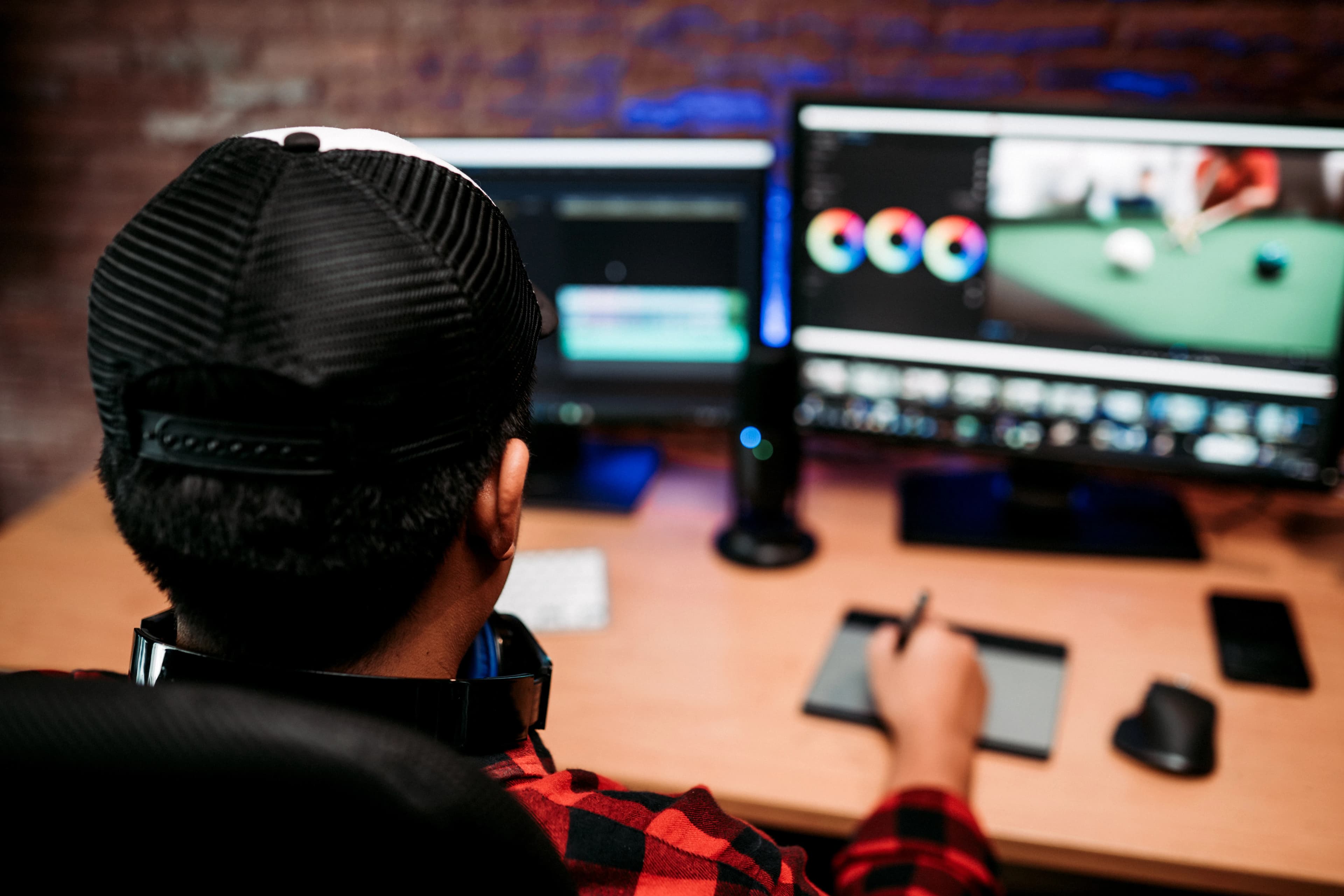 Ev stüdyosunda iki monitörde video kurgusu yapan bir editör