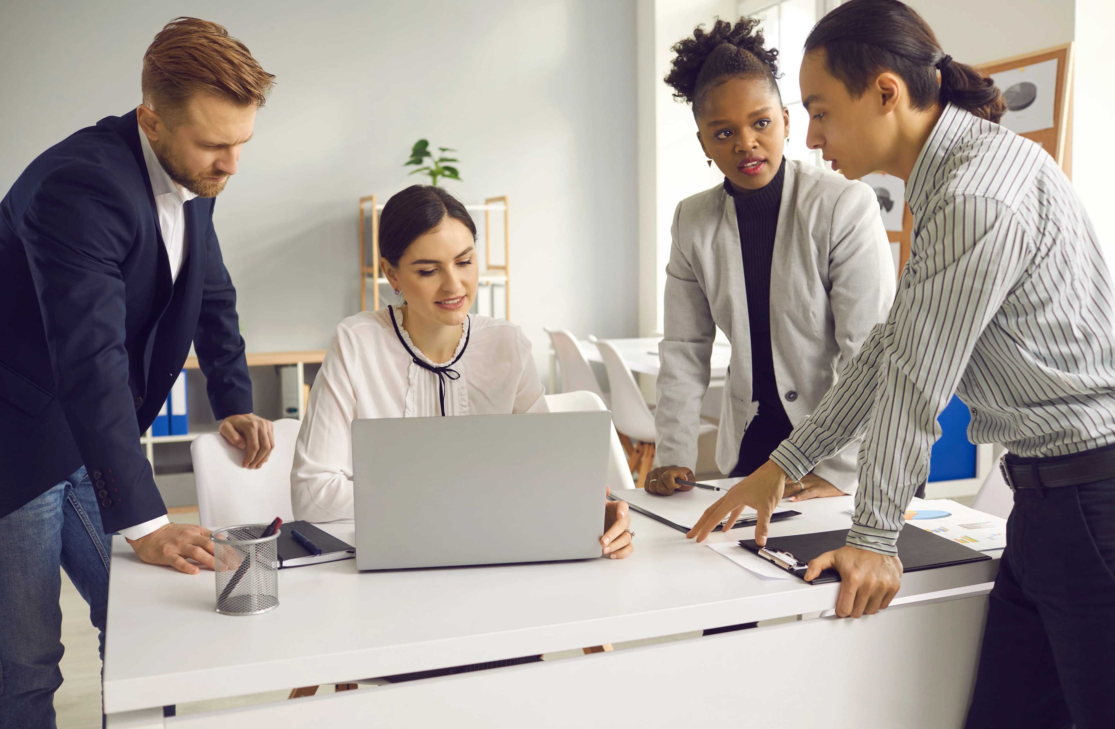 A team gathered around a laptop in an office planning a campaign