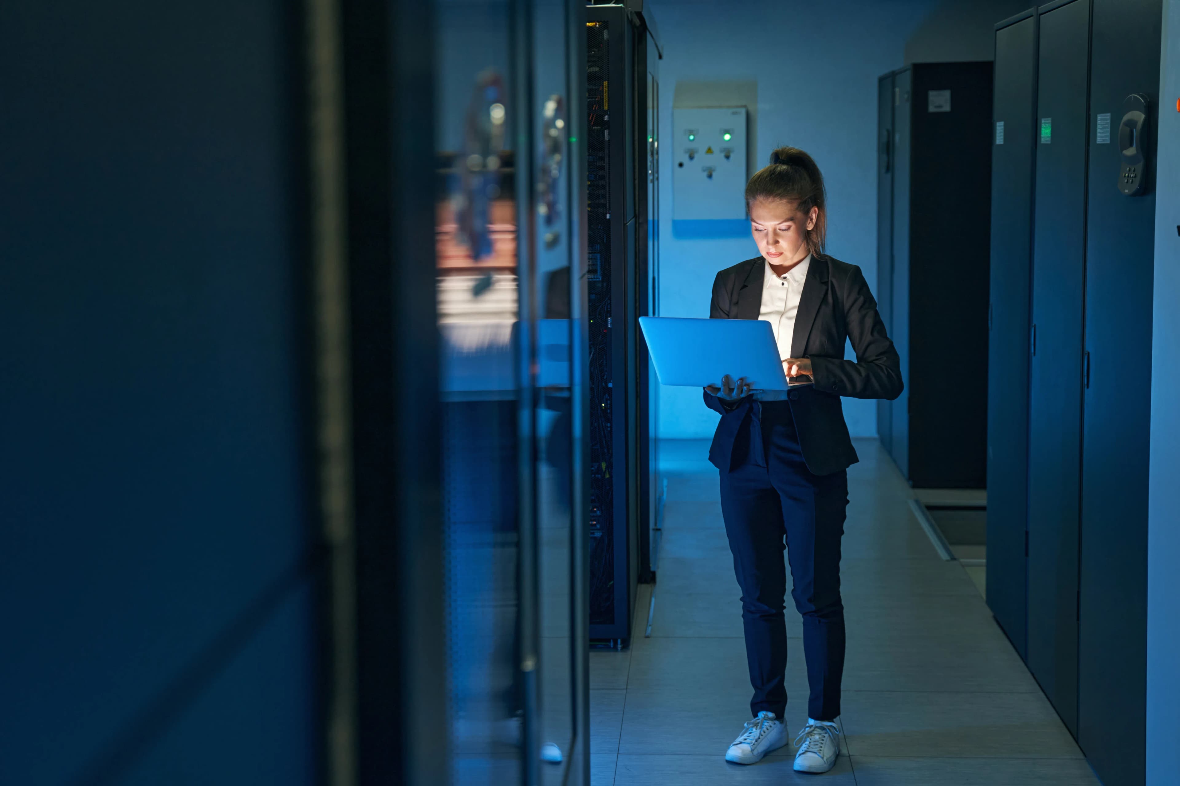 Technician checking servers with a laptop between racks in a data centre