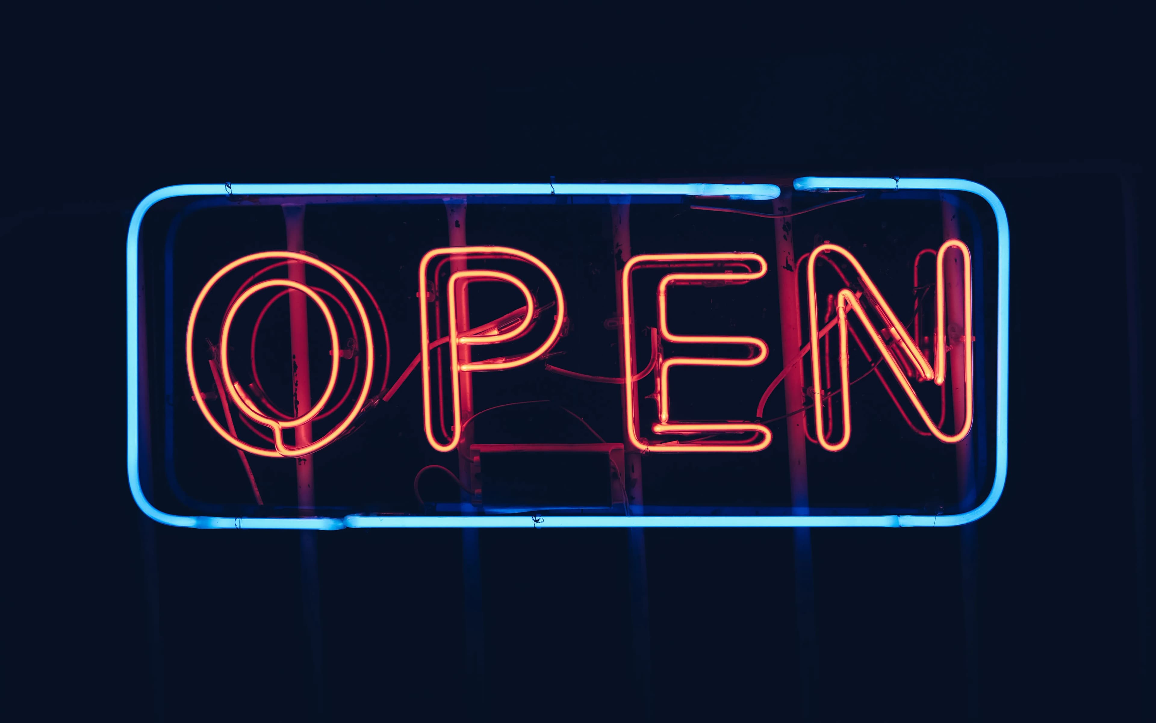 A neon open sign glowing in the dark at night