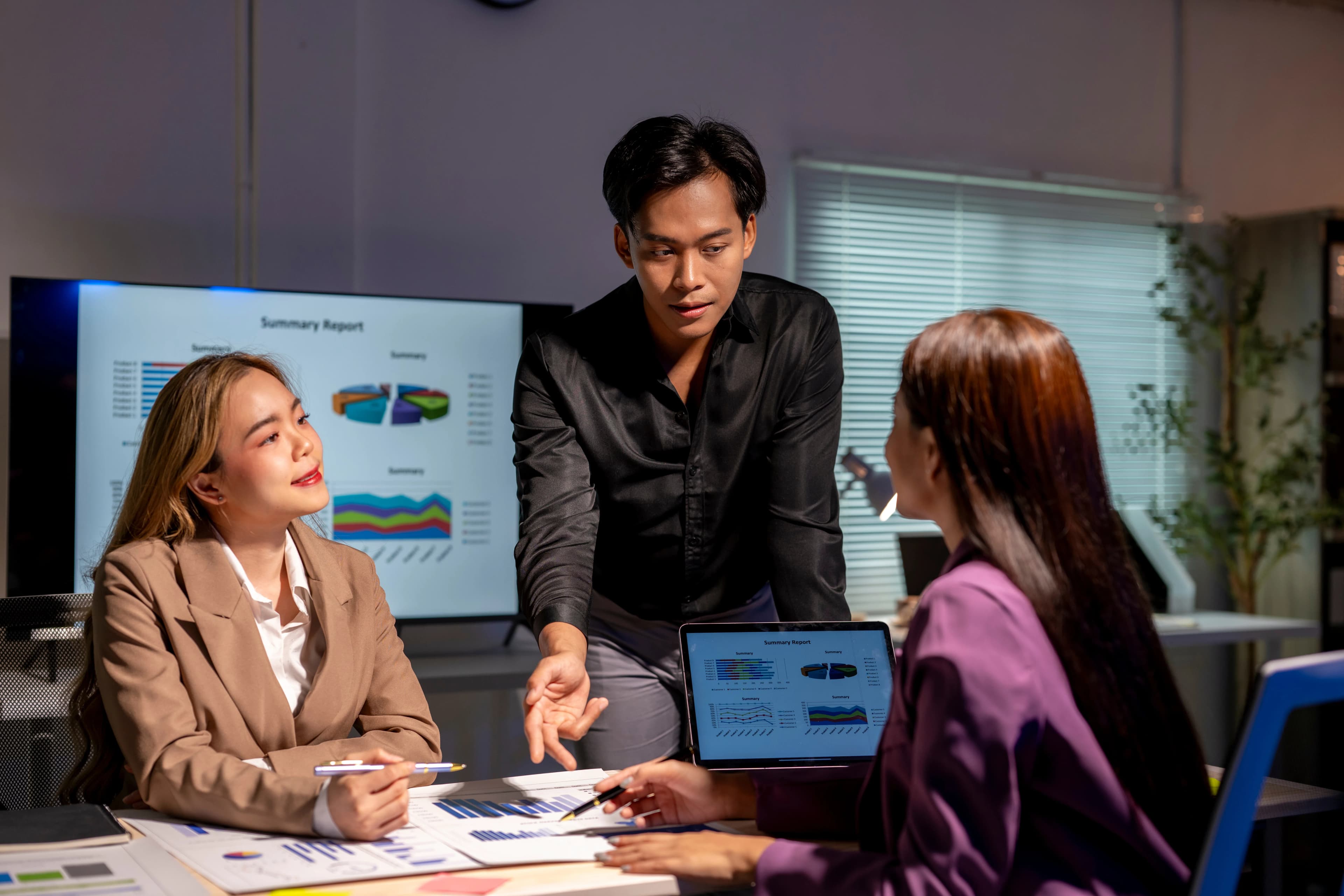 A team reviewing charts on a laptop and documents at a meeting table