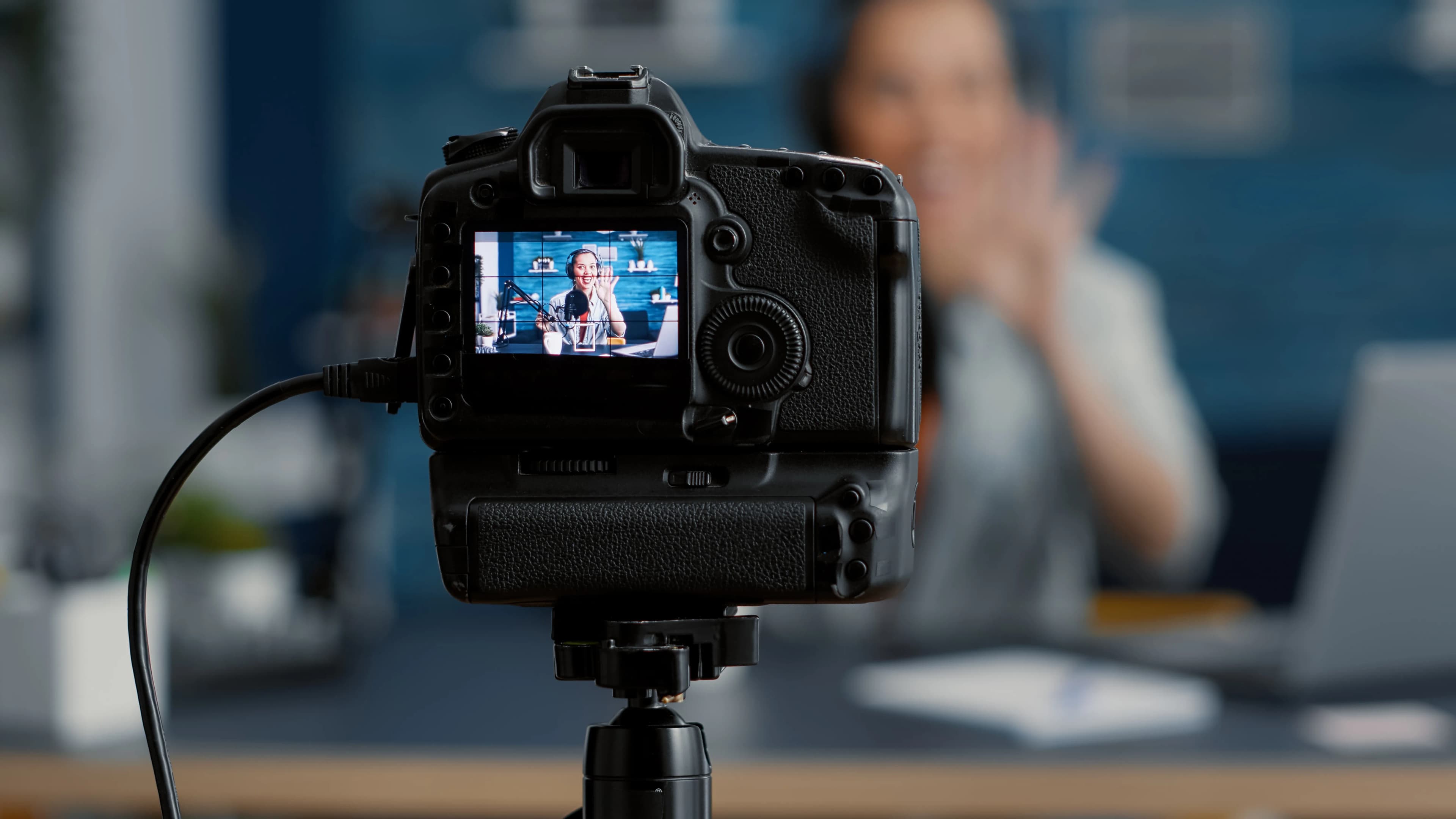 A content creator talking to the camera, seen on the camera's screen on a tripod